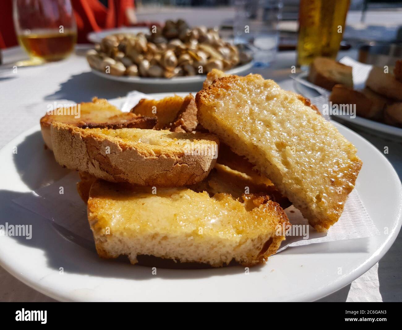 Sliced toasted bread with butter, with cooked snails in the background Stock Photo