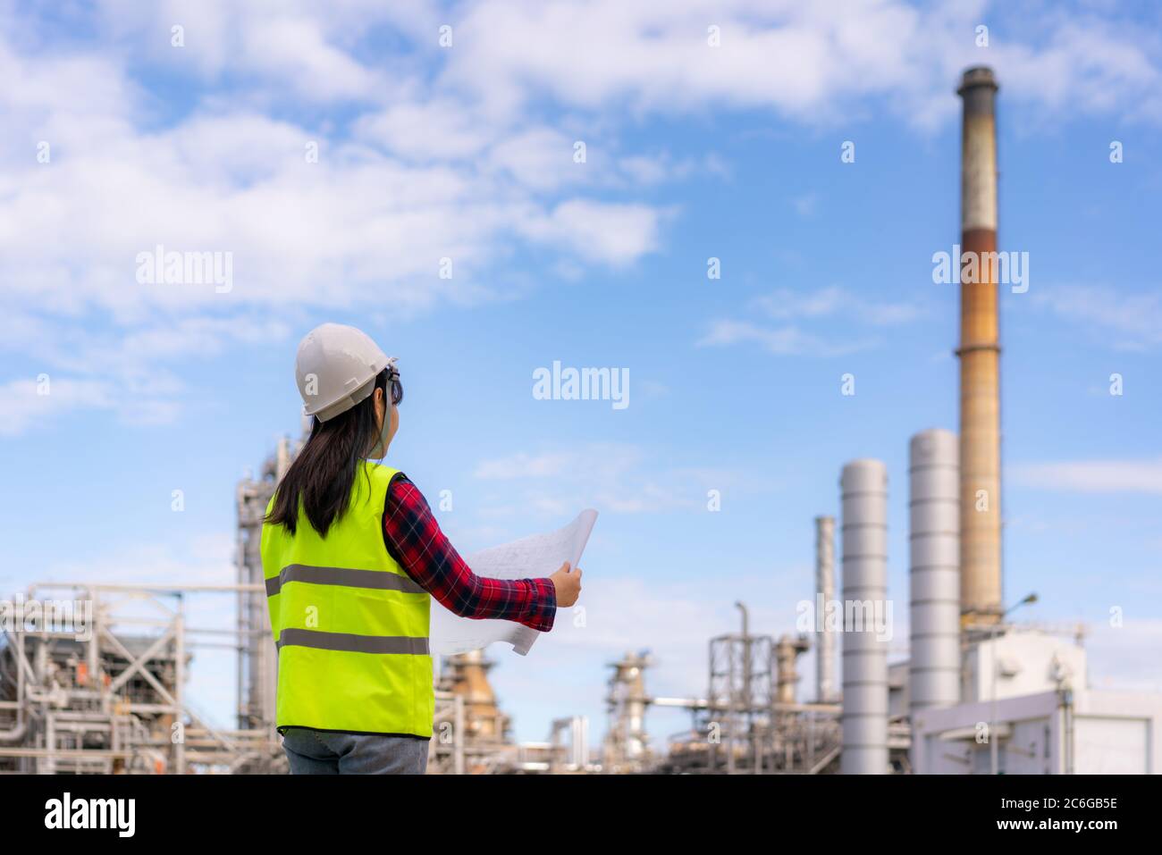Asian woman engineer work control at power plant energy industry manufacturing oil refinery. Engineering check plant with blueprint. Stock Photo