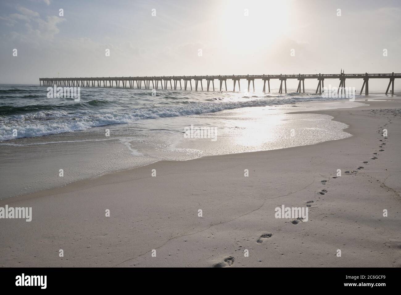 Tide recedes on Pensacola beach leaving fresh sand for new footprints heading towards Pensacola Pier on Florida's Panhandle coast Stock Photo