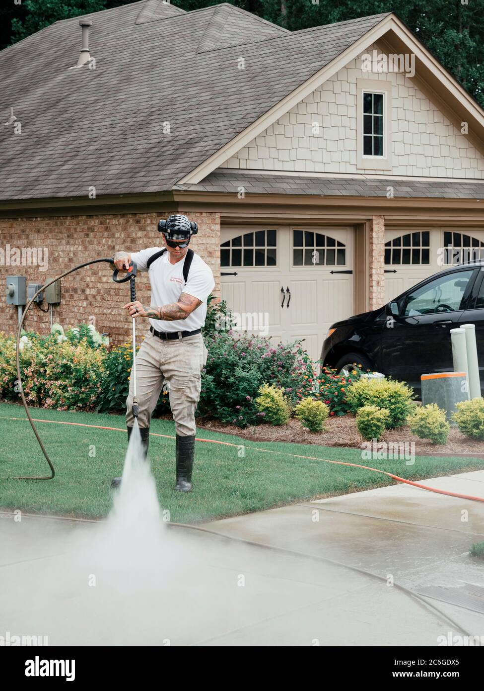 Man pressure washing or power washing or cleaning a concrete driveway and sidewalk in Montgomery Alabama, USA. Stock Photo