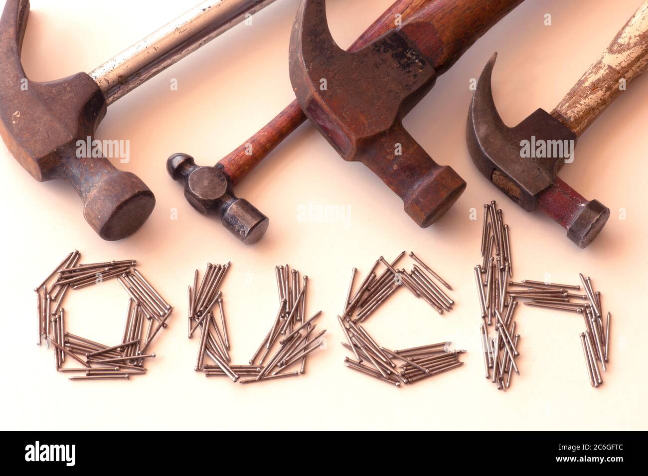 SONY DSC The word 'OUCH' spelled out in nails with 4 used hammers above the nails warning to be careful when you pound. Stock Photo