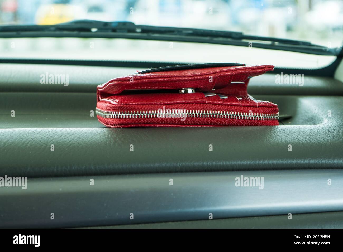 Red wallet left on dashboard of car. Stock Photo