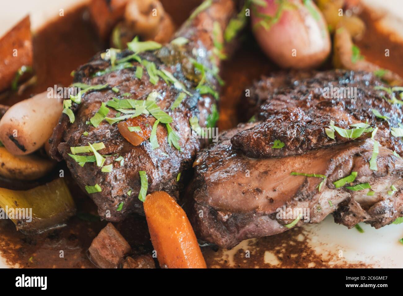 Coq au Vin, French Chicken Braised in Red Wine, on a White Plate Stock Photo
