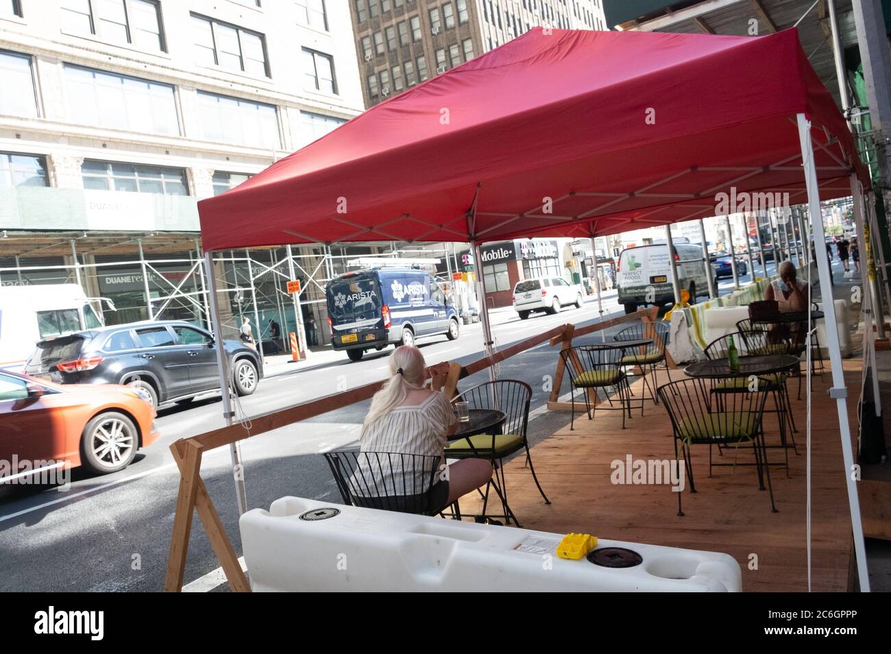 New York, United States. 08th July, 2020. A woman sits in an outdoor dinning setup of a Manhattan restaurant as the city enters phase 3 of reopening amid the coronavirus pandemic.As New York City enters phase 3 of reopening retail stores for indoor shopping, restaurants have been postponed for indoor dinning. Meanwhile Black Lives Matter protests continue in the city as the Mayor along with a group of people painted a large Black Lives Matter mural in front of Trump Tower on 5th Ave. Credit: SOPA Images Limited/Alamy Live News Stock Photo