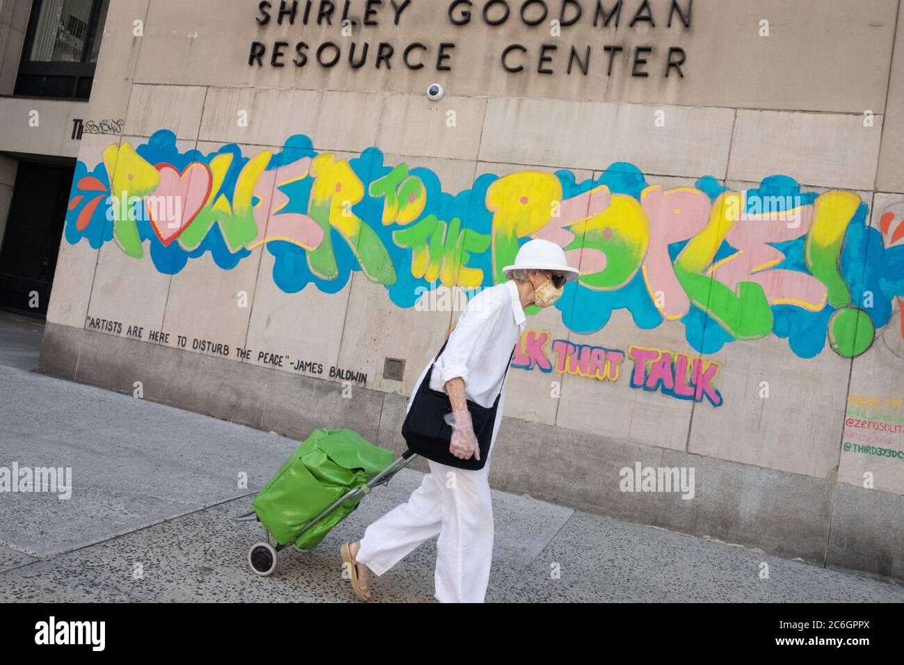 New York, United States. 08th July, 2020. A woman wearing a face mask and glove walks past a mural saying Power to the People as the city enters phase 3 of reopening amid the coronavirus pandemic.As New York City enters phase 3 of reopening retail stores for indoor shopping, restaurants have been postponed for indoor dinning. Meanwhile Black Lives Matter protests continue in the city as the Mayor along with a group of people painted a large Black Lives Matter mural in front of Trump Tower on 5th Ave. Credit: SOPA Images Limited/Alamy Live News Stock Photo