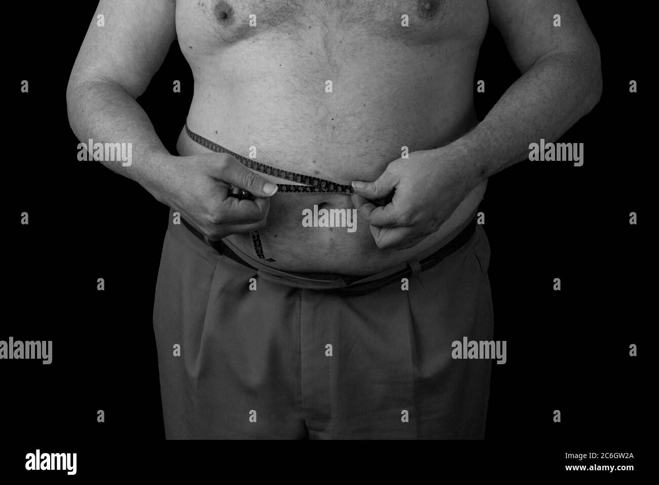 Fat man holding a measuring tape, measure your abdomen. Weight Loss. Black and white Photo on a black background isolated Stock Photo