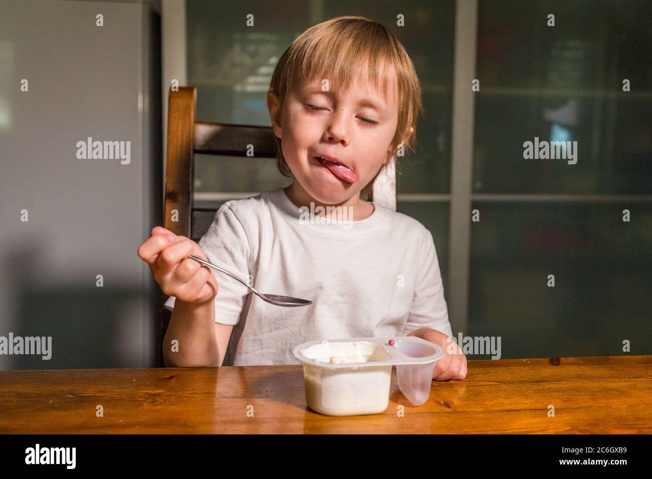 Adorable baby girl eating cottage cheese from spoon, healthy milk snack