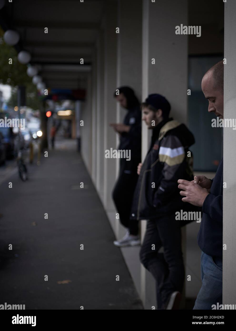 Street photography. People in Sydney looking at their phones while they wait for a bus. Stock Photo