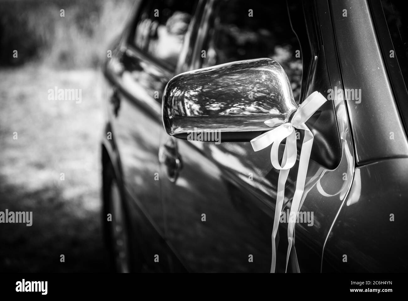 Mirror of wedding car decorated with ribbon. Black and white photo. Selective focus. Shallow DOF Stock Photo