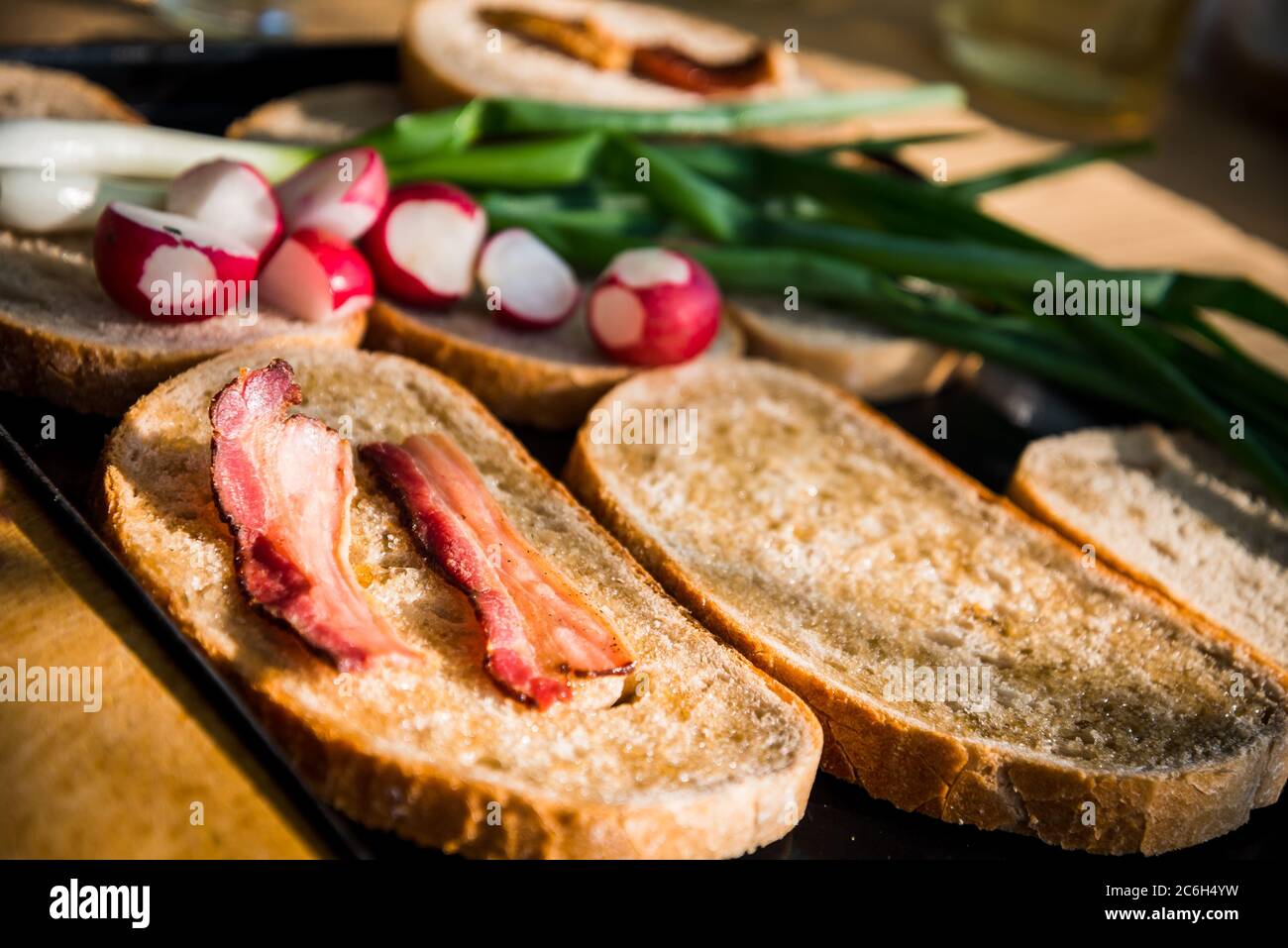 Grilled bacon slice on fatty bread with green onion and fresh radish on a hungarian summer grill party. Barbeque background Stock Photo