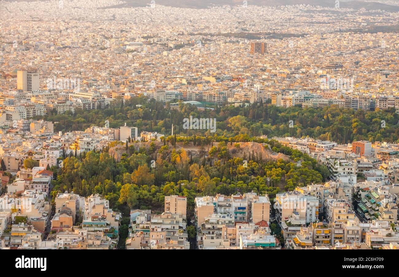 Greece. Warm summer evening over the rooftops of Athens. Residential buildings and narrow streets. Green parks. Aerial view Stock Photo