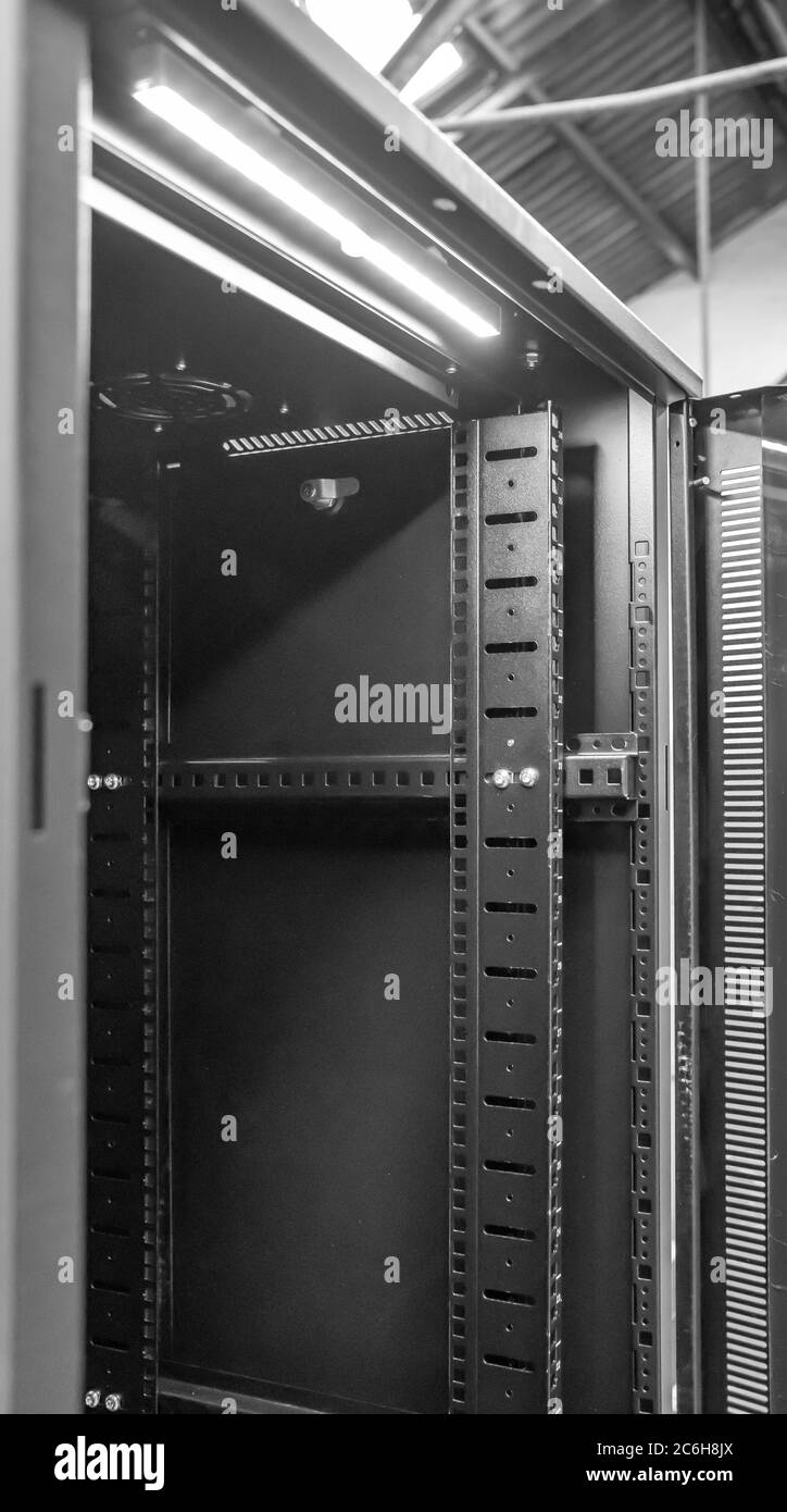 Detailed image of a Computer and Network server cabinet showing the front meshed door open, seen in a data centre for hosting servers. Stock Photo