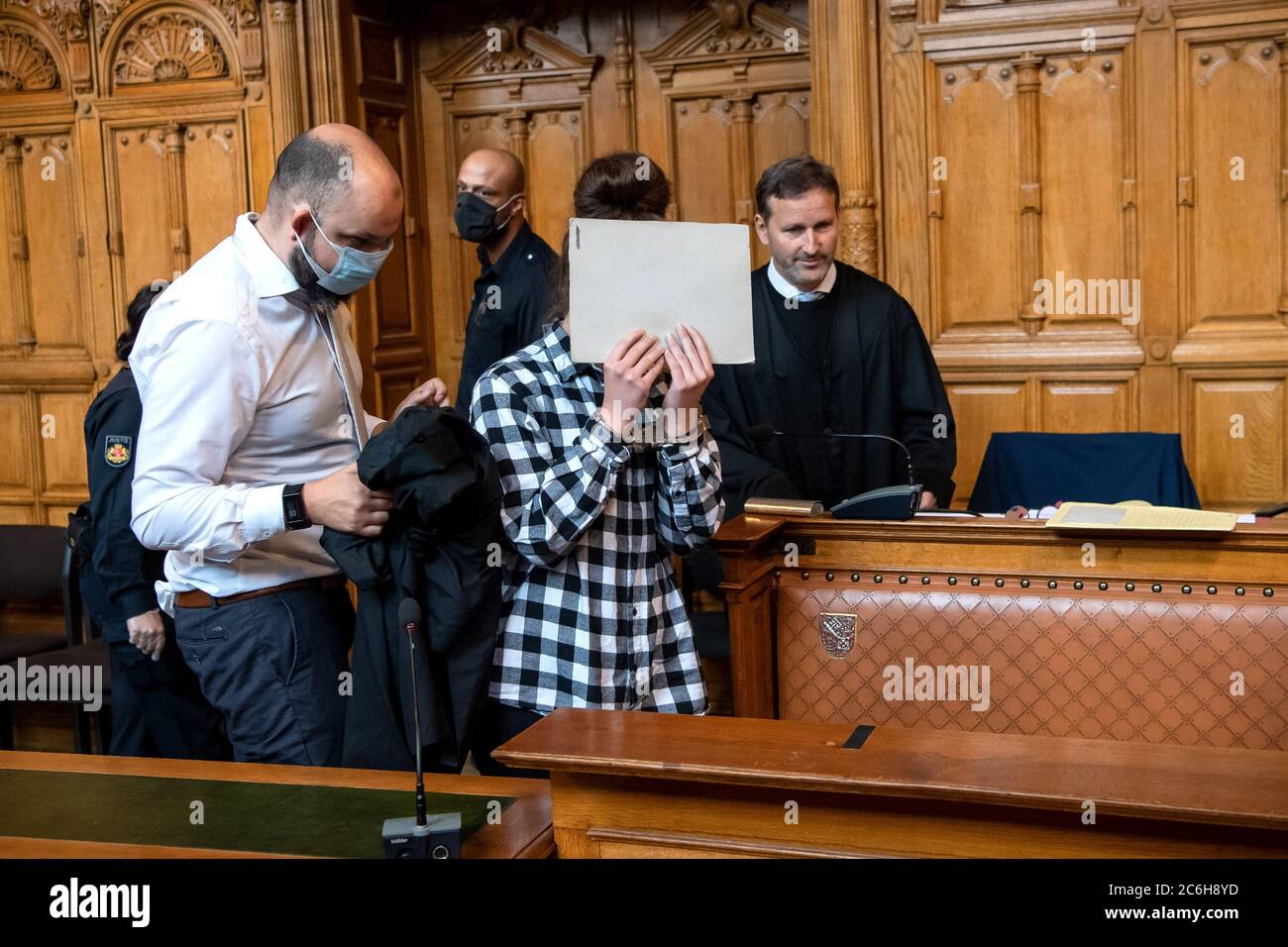 Bremen, Germany. 10th July, 2020. The defendant in the murder trial is accompanied before the start of the trial by her lawyers Mario Kroschewski (l) and Stefan Hoffmann (r) into the courtroom of the regional court. The public prosecutor accuses the 20-year-old woman of having used a sharp object to make deep and wide cuts to her 24-year-old boyfriend. The man bled to death. Credit: Sina Schuldt/dpa/Alamy Live News Stock Photo