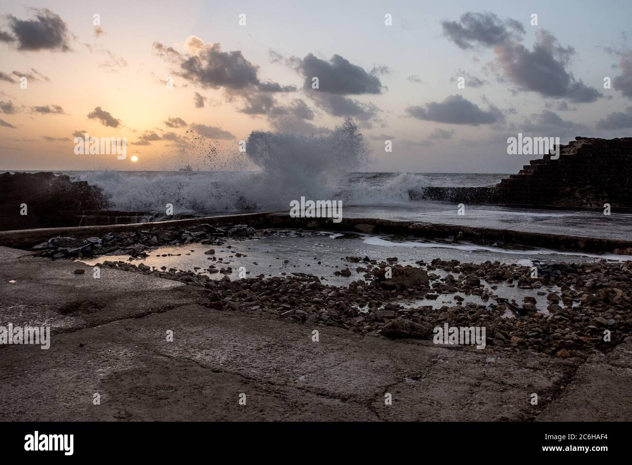 The ancient port of Caesarea, Israel at Sunset. Waves are breaking on the breakwater Stock Photo