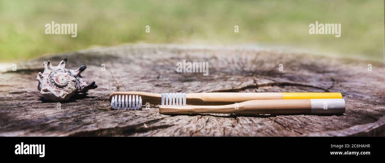 Two white and yellow eco friendly bamboo wooden toothbrushes on wooden ...