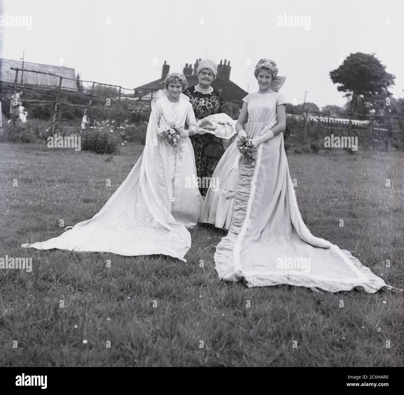 1950s, historical, local teenage girls, the Rose Queen and her precedessor, standing in a park field in their gowns at Farnworth, Bolton, Lancashire, England, UK. Dating back to the 1880s, the annual Rose Queen festival, held in June, became a major annual event in many towns and villages across the UK, especially in Lancashire, known as the red rose county, following the 1455-87 Wars of the Roses. Stock Photo