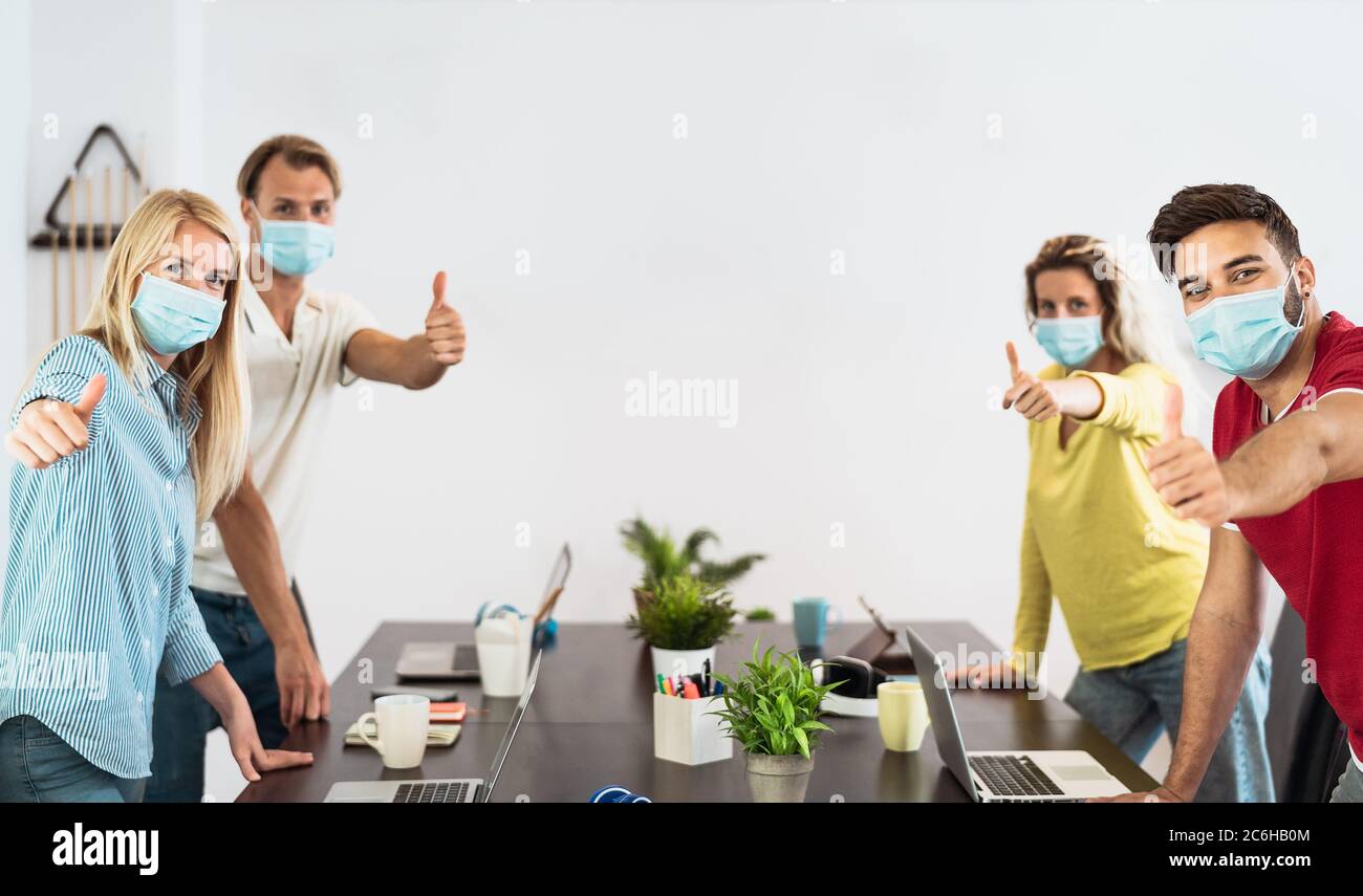 Young people working in co-working creative space wearing surgical mask protection for preventing corona virus spread Stock Photo