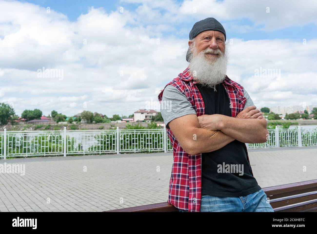Experienced senior old man with beard on street posing and smiling, portrait Stock Photo