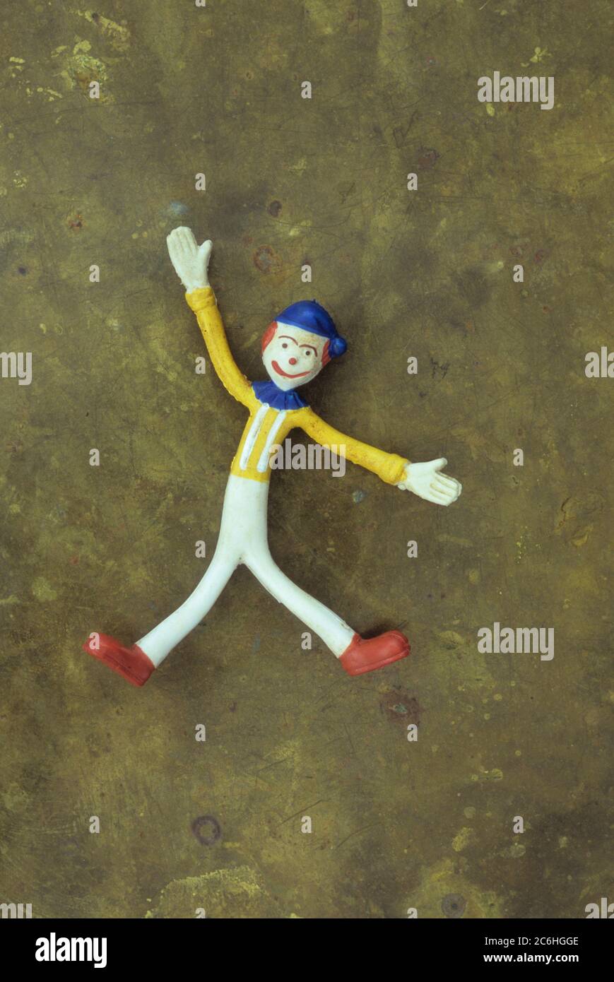 Bendy figure model of happy clown or teenager with arms outspread and legs apart with background of tarnished brass Stock Photo