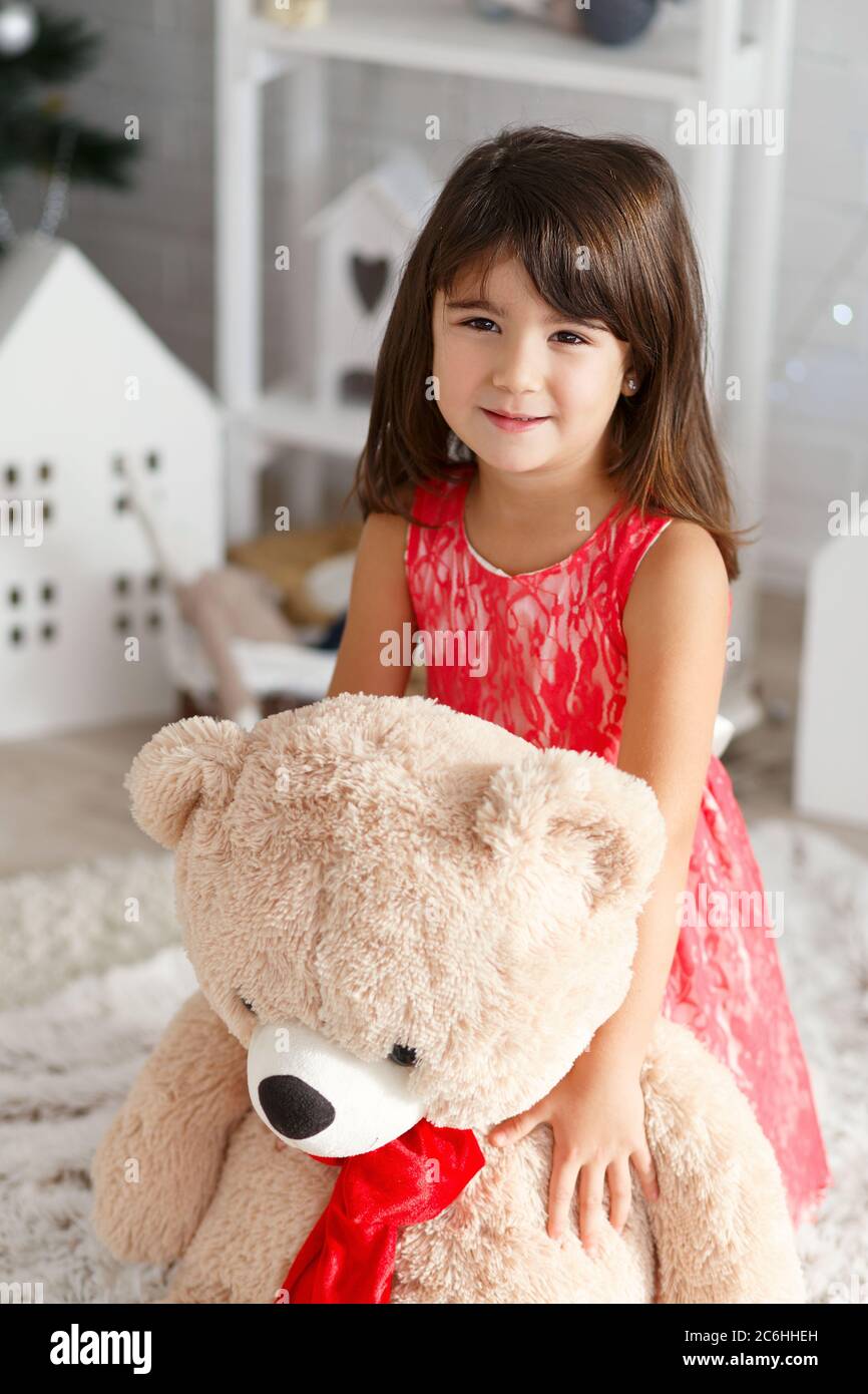 Portrait Of A Cute Little Brunette Girl Hugging A Soft Big Teddy Bear In Interior With Christmas Decorations Stock Photo Alamy