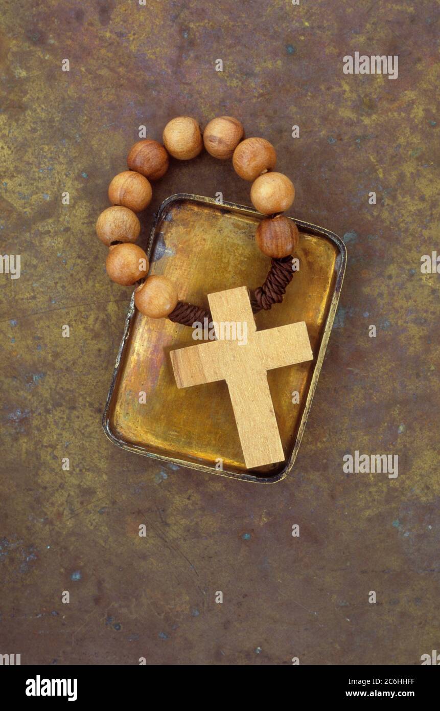 Small brass lid containing wooden crucifix with rosary beads Stock Photo