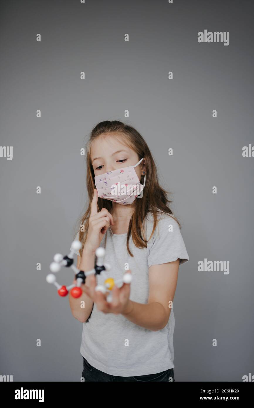 beautiful young girl with nose mouth mask is holding molecule model Stock Photo