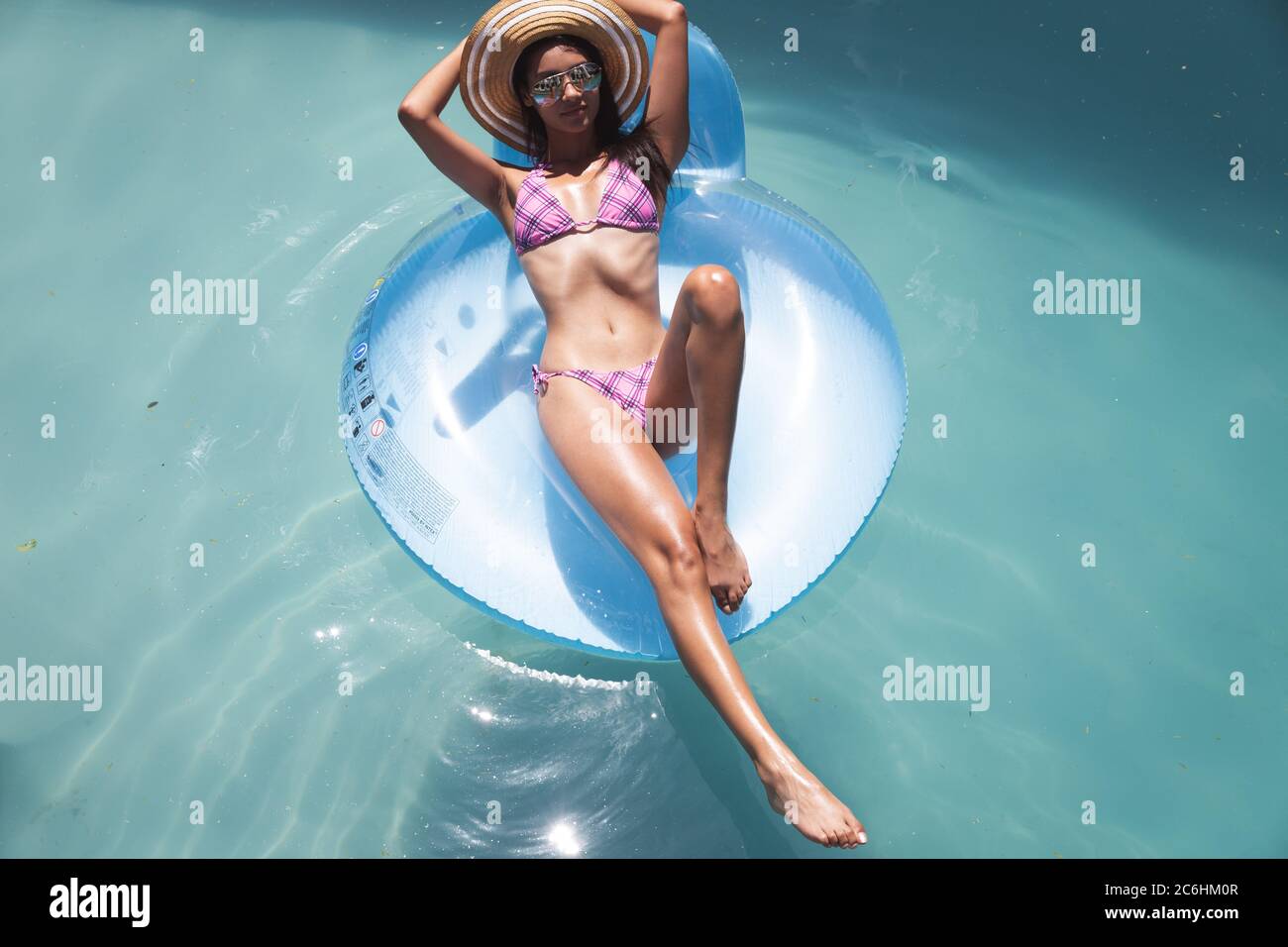 Woman floating on a inflatable ring in the swimming pool Stock Photo