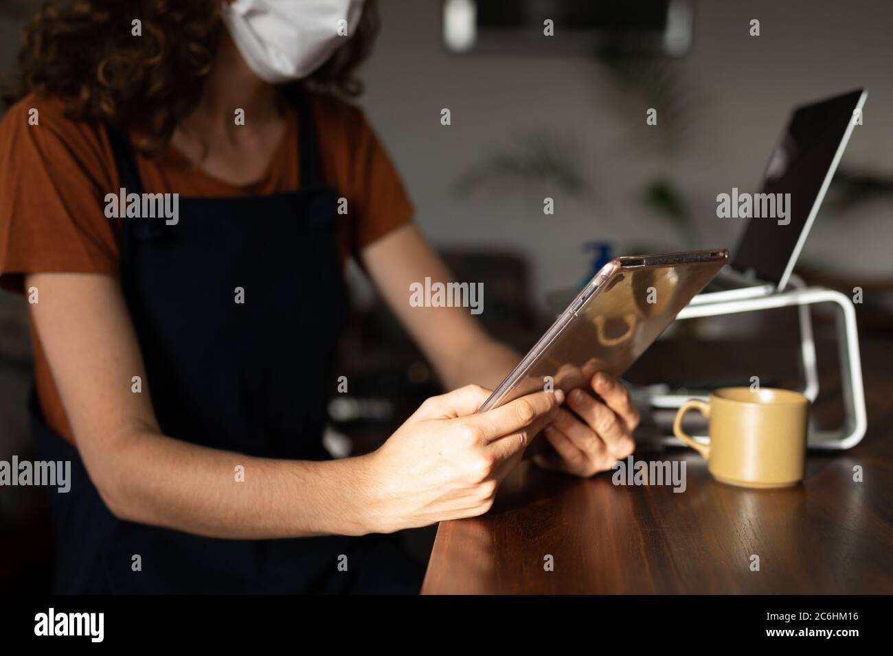 Mid section of woman wearing face mask using digital tablet at home Stock Photo