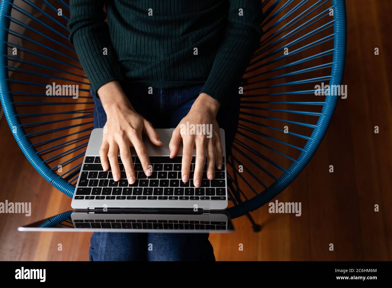 Mid section of woman using laptop sitting on a chair Stock Photo