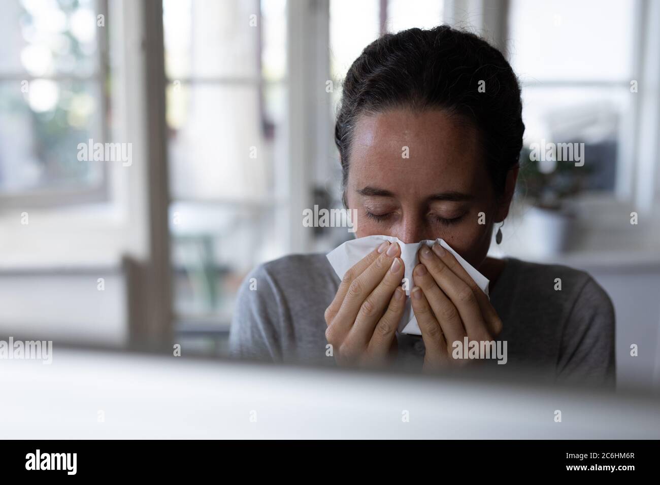 Woman blowing her nose at home Stock Photo