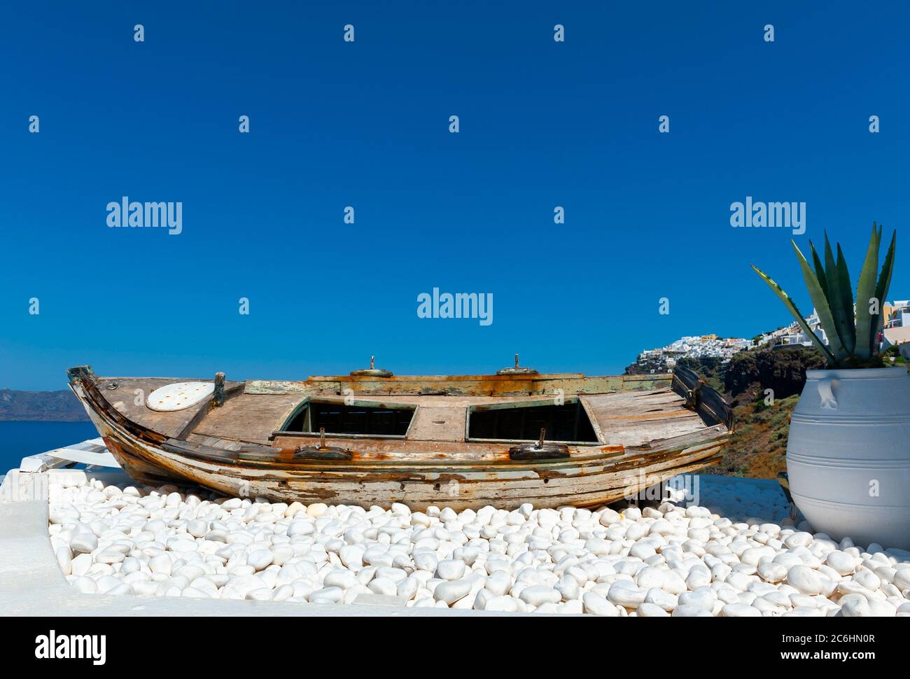 Santorini Greece,Greek islands,Cyclades. old boat displayed on white stones against a blue sky Stock Photo