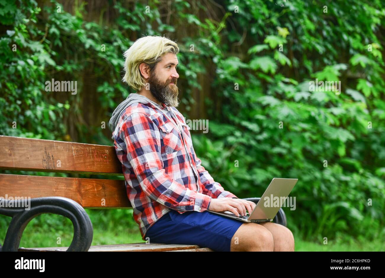 Remote job. Online shopping. Agile business. Bearded guy sit bench park nature background. Work and relax. Working online. Hipster inspired work in park. Fresh air. Mobile internet. Modern laptop. Stock Photo