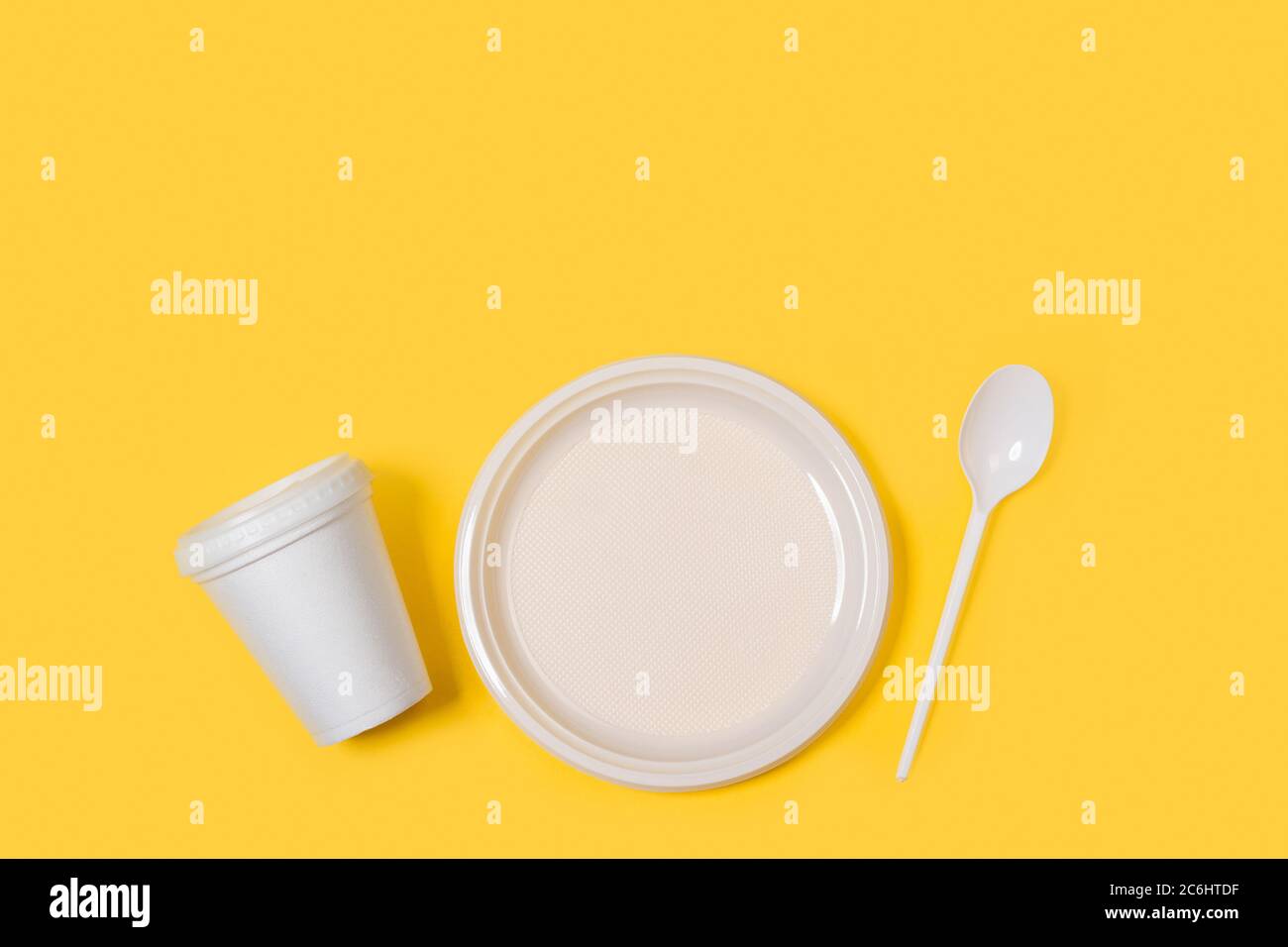 Disposable plastic white tableware set on a yellow background in a directly above view Stock Photo