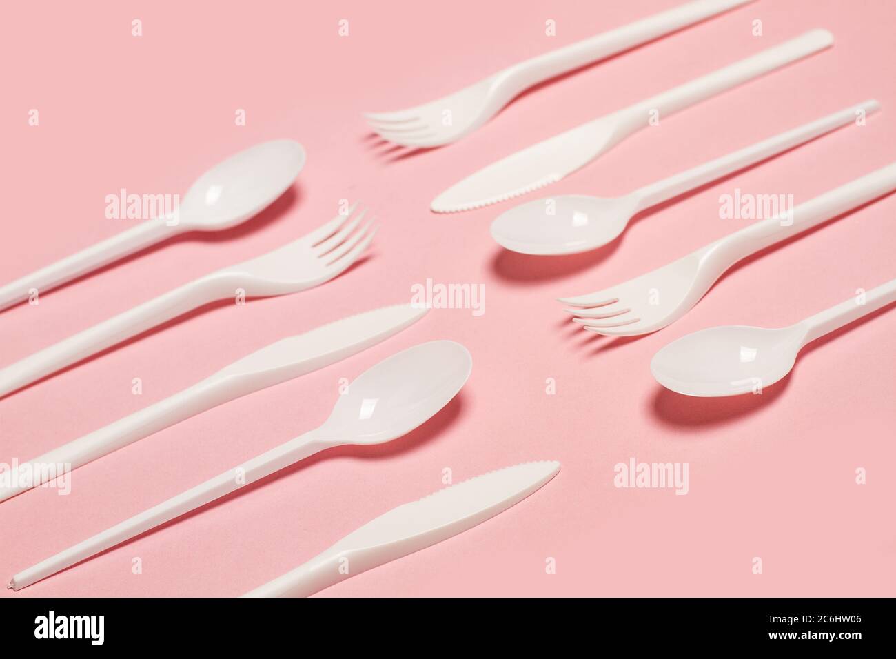 Disposable white plastic flatware on a pink background in a top view Stock Photo