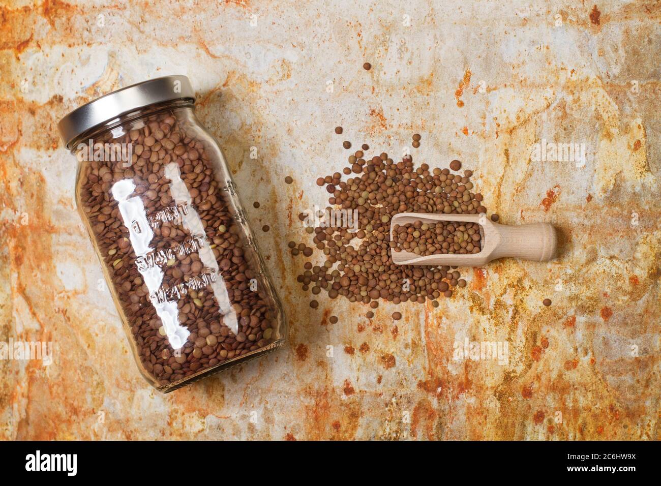 Lentils in a crystal jar and on a rusty metal background in a top view Stock Photo