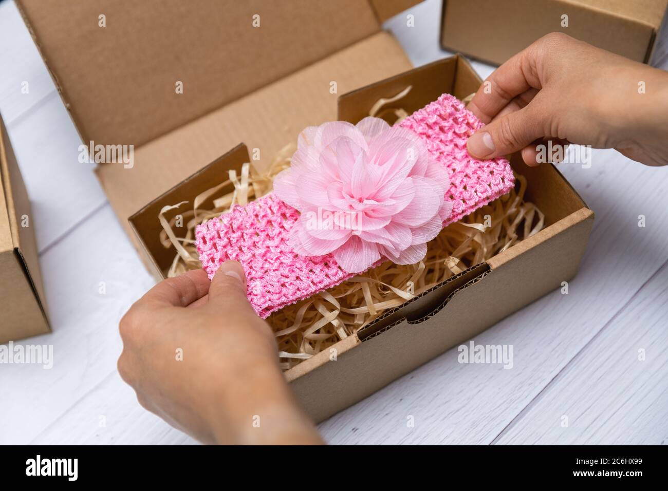 craft business - woman packing handmade baby floral headband in cardboard box for shipping Stock Photo