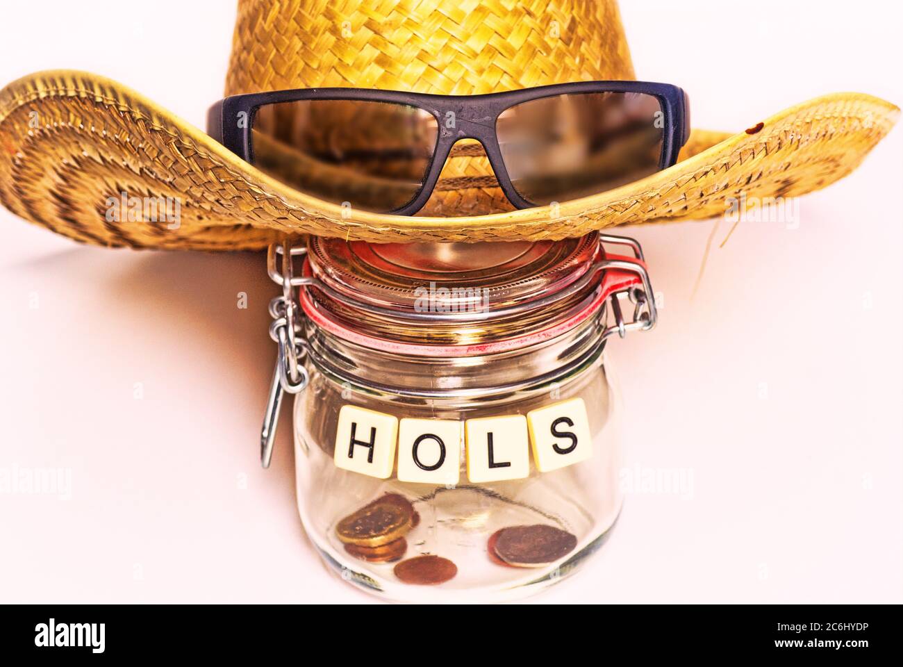 Financial concept image. Cost of  Covid 19 to economy and savings.  Almost empty jar for holiday savings. Holiday hat, sun glasses.   None. Poverty. Stock Photo