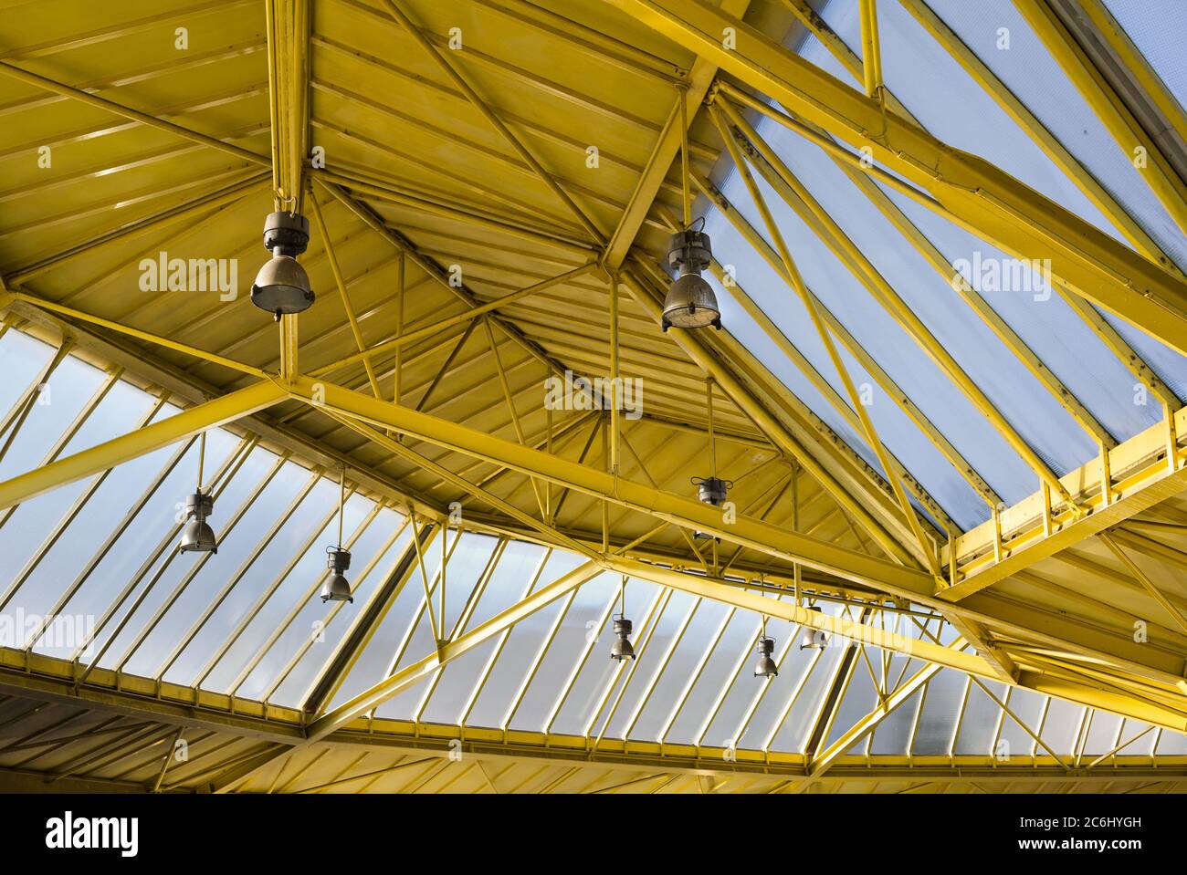 Metallic construction of ceiling and beam in factory and industrial building. Big windows and lights. Sheet metal has yellow color. Geometrical lines Stock Photo