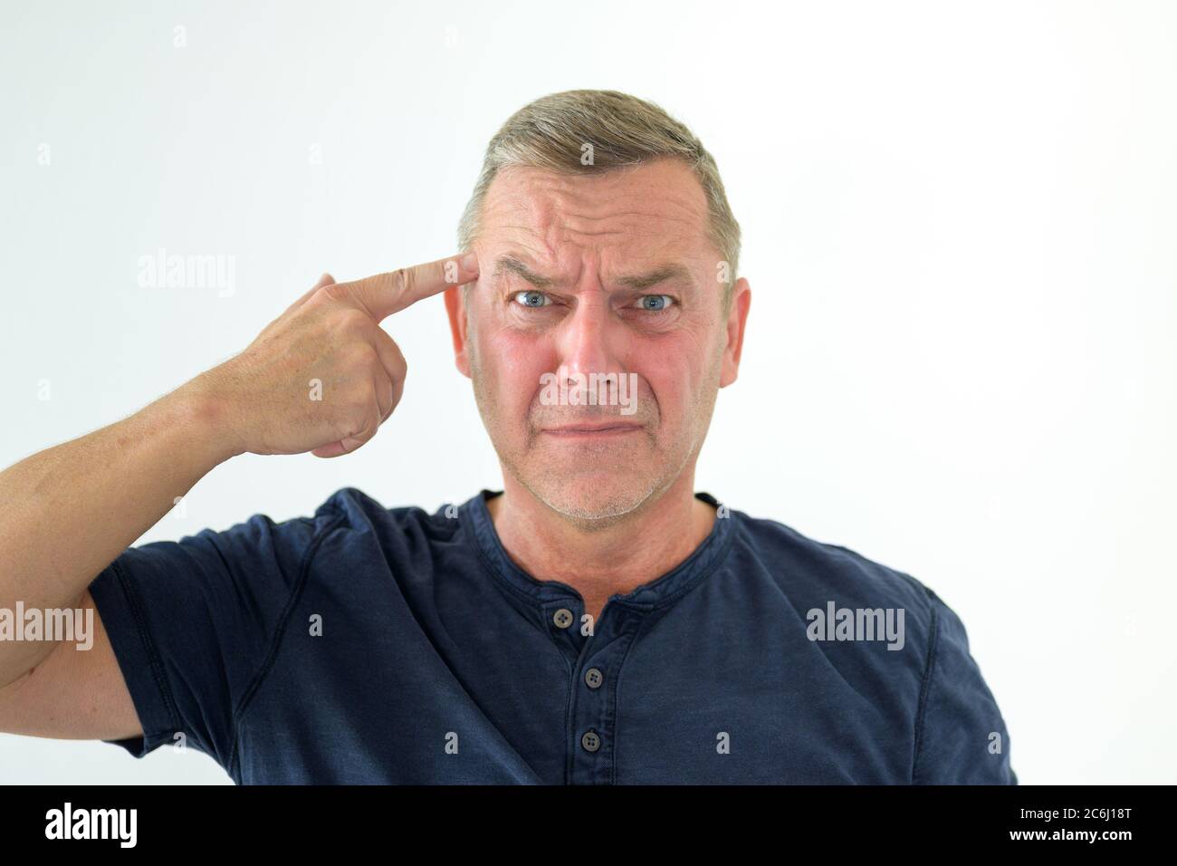 Angry man making a threatening gun gesture with his hand pointing at his own forehead Stock Photo