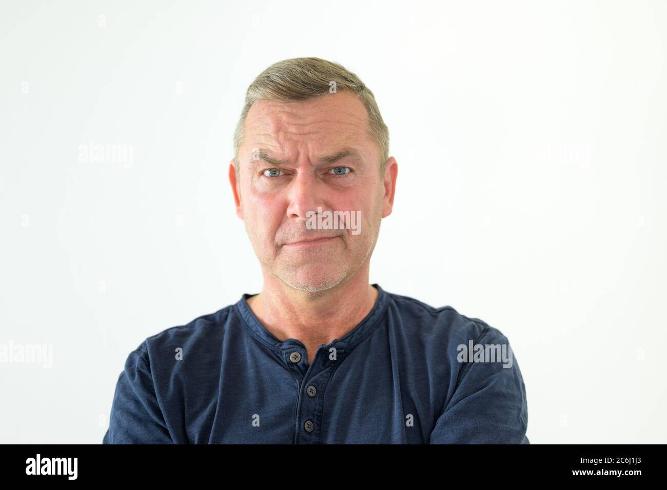 Perplexed man staring at the camera in confusion frowning with a wry smile in a head and shoulders portrait on a white background Stock Photo
