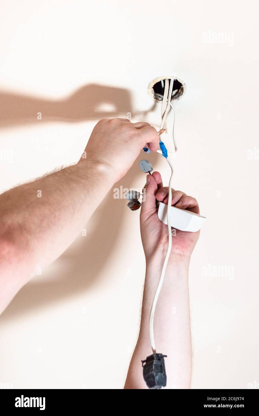 electrician mounts electrical system for halogen lamp of false ceiling Stock Photo