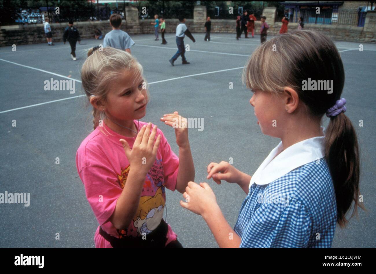 Deaf primary school girls using sign language in the playground Stock