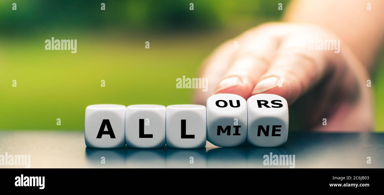 Hand turns dice and changes the expression 'all mine' to 'all ours'. Stock Photo