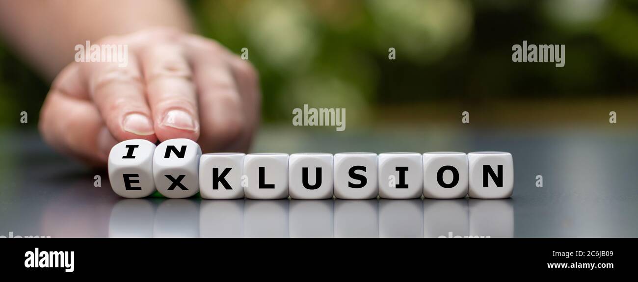 Symbol for a better inclusion. Hand turns dice and changes the German word 'Exklusion' (exclusion) to 'Inklusion' (inclusion). Stock Photo