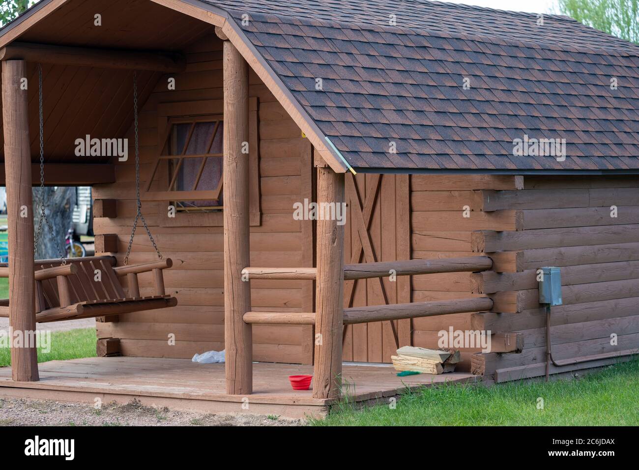 Exterior of an adorable camping cabin with a porch swing and window at