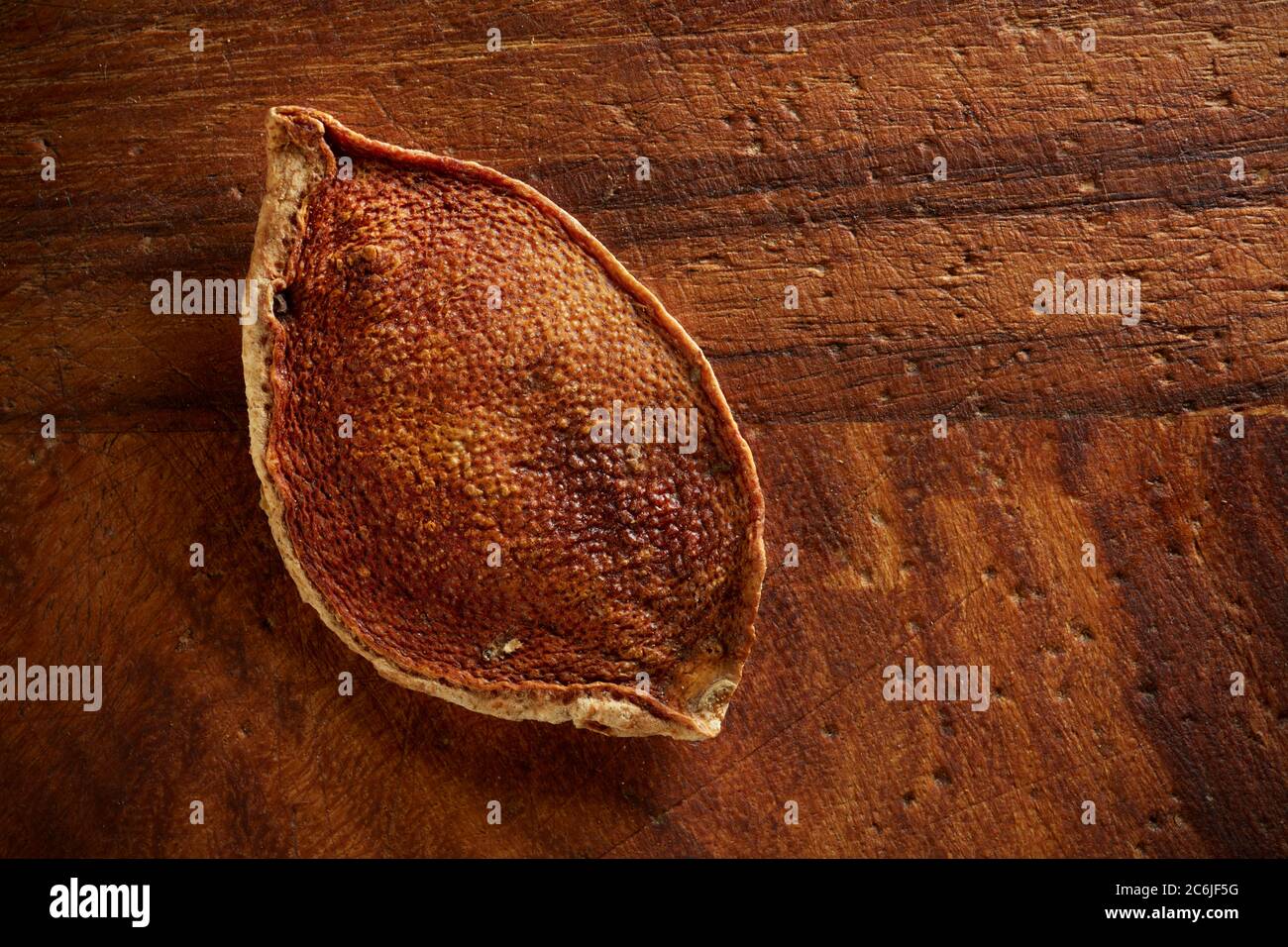 Single piece of dried orange rind on old wooden board. Stock Photo