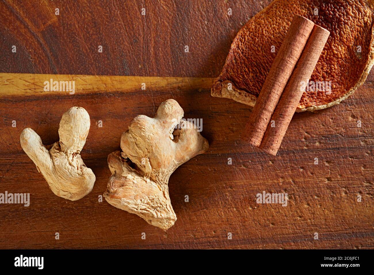 Dry mulling spices (ginger, orange rind, cinnamon stick) on wooden board. Stock Photo