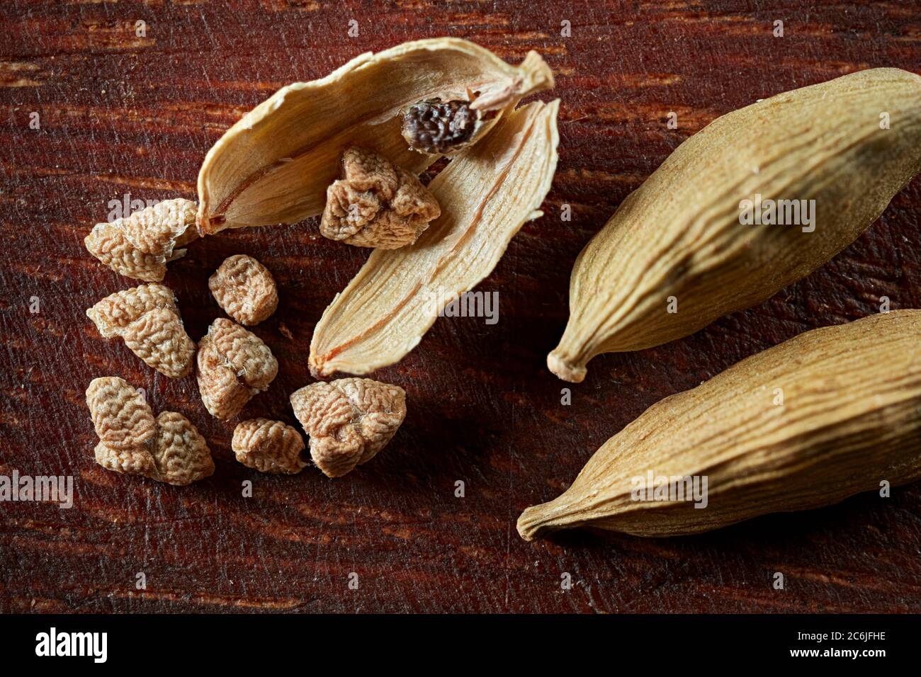 Close up of dried cardamom pods and seeds on wooden board. Stock Photo