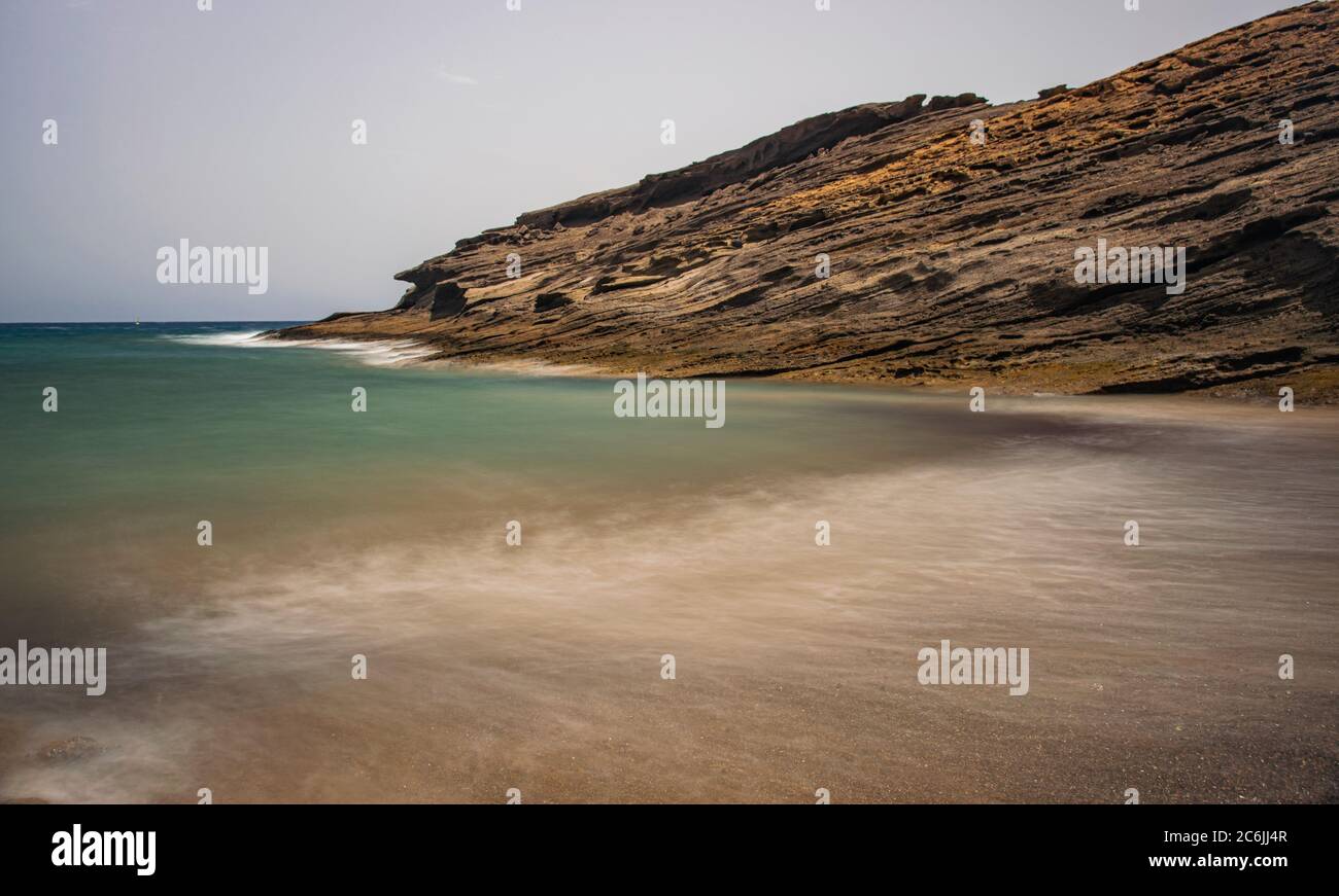 Secret beach in El Medano, long exposure, Volcanic rocks formation eroded by the wind and sea, Tenerife, Canary islands, Spain Stock Photo
