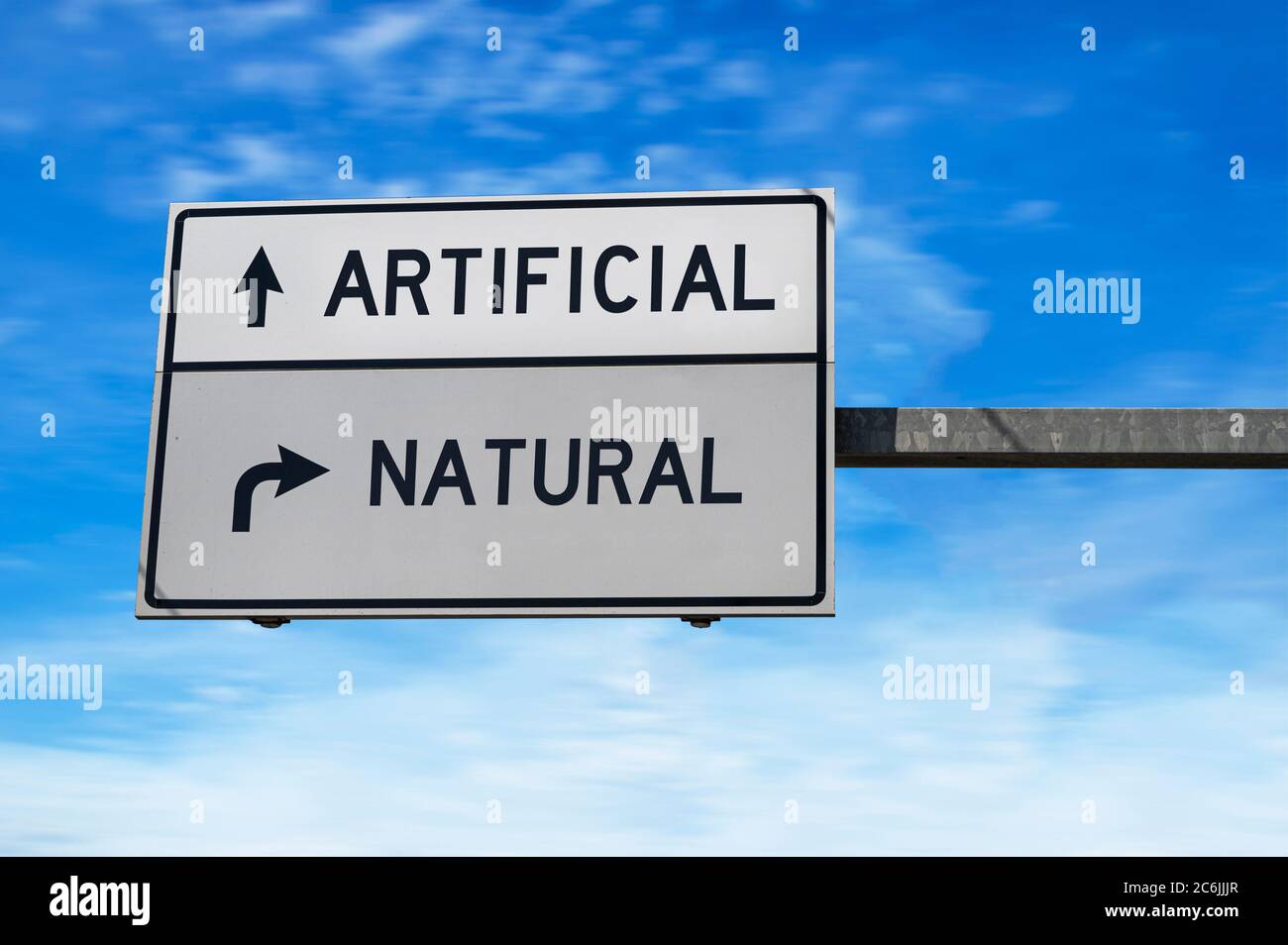 Artificial versus natural. White two street signs with arrow on metal pole. Directional road, Crossroads Road Sign, Two Arrow. Blue sky background. Stock Photo